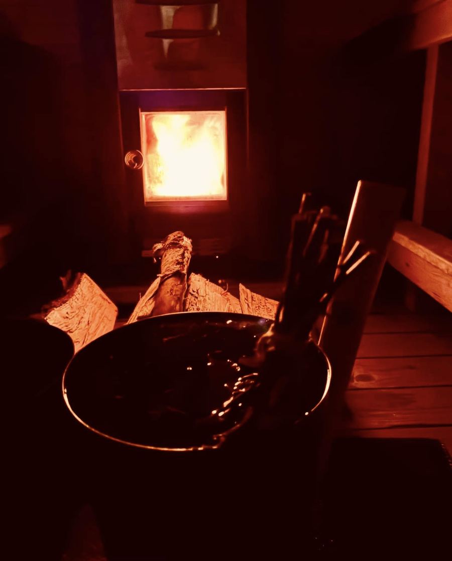 Närbild på brasan i bastuns vedeldade kamin.
